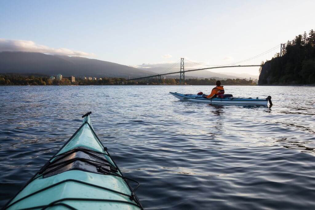 People kayaking in the waters around Stanley Park, Lions Gate Bridge, Vancouver 