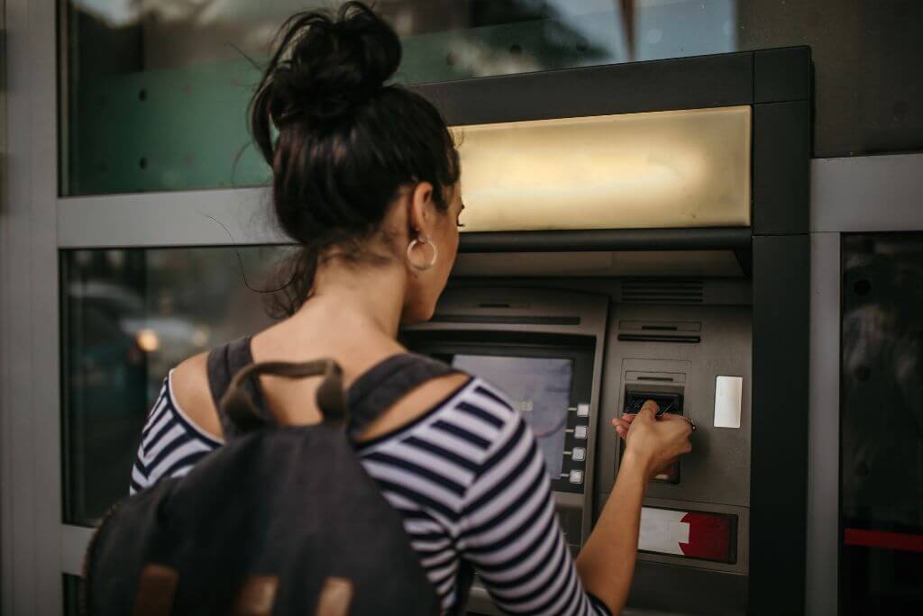 A woman using an ATM machine while traveling