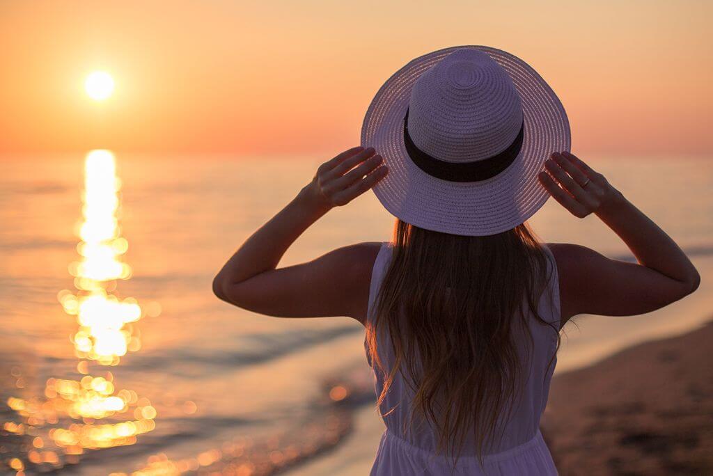 A woman in a white dress and a hat on a beach, is the DR safe