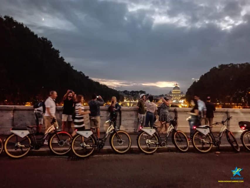 Rome night tour with an E-Bike, Rome, Italy, people standing on a bridge with E-Bikes, Night Tours Rome