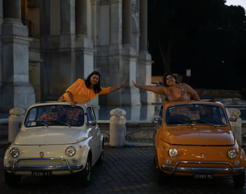 Fiat 500 Tour in Rome, two cars, two women in two cars giving each other high five