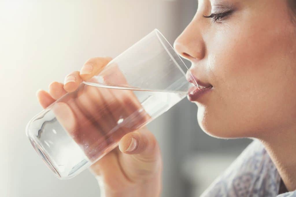 A woman drinking a glass of water, drinking water