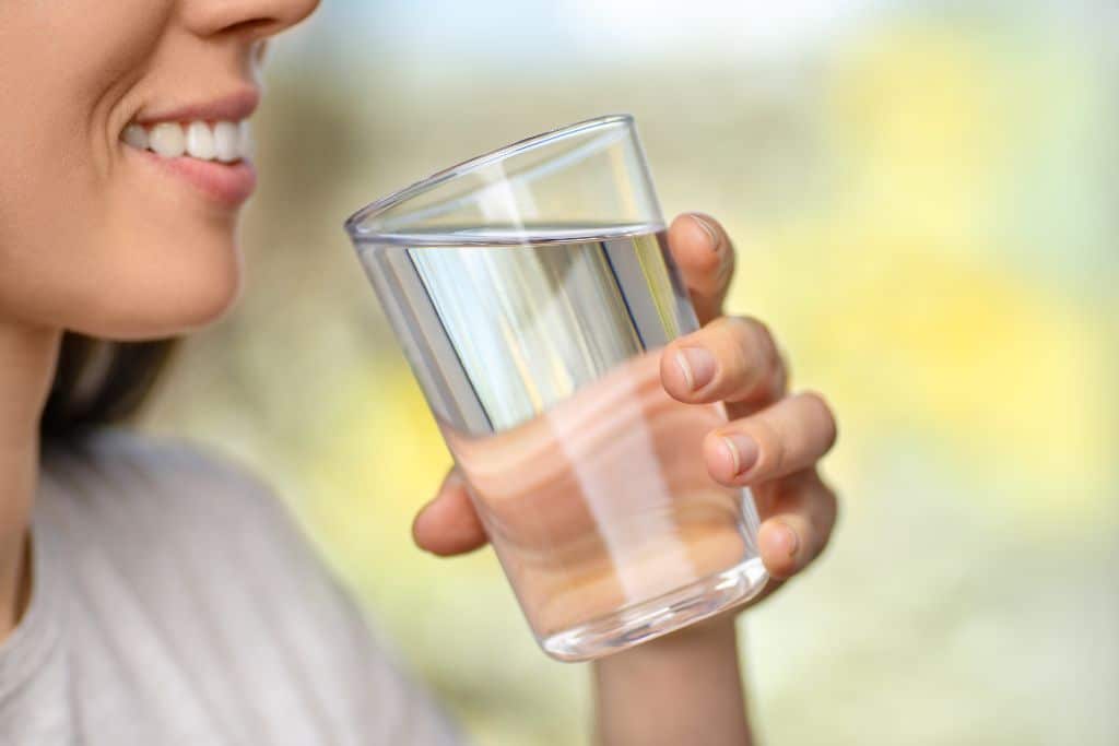 a woman drinking a glass of water, water in a glass