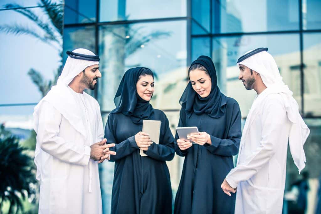 Two arab men and two arab women standing in a semi circle talking, What Are People From Dubai Called?