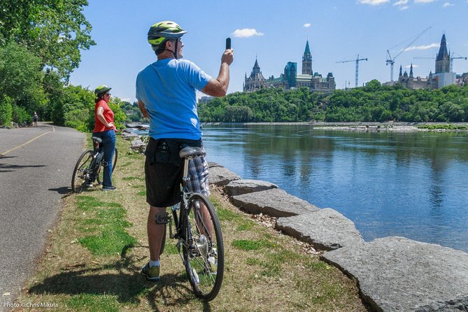 A couple taking pictures on a bike tour in Ottawa, river, Parliament Hill