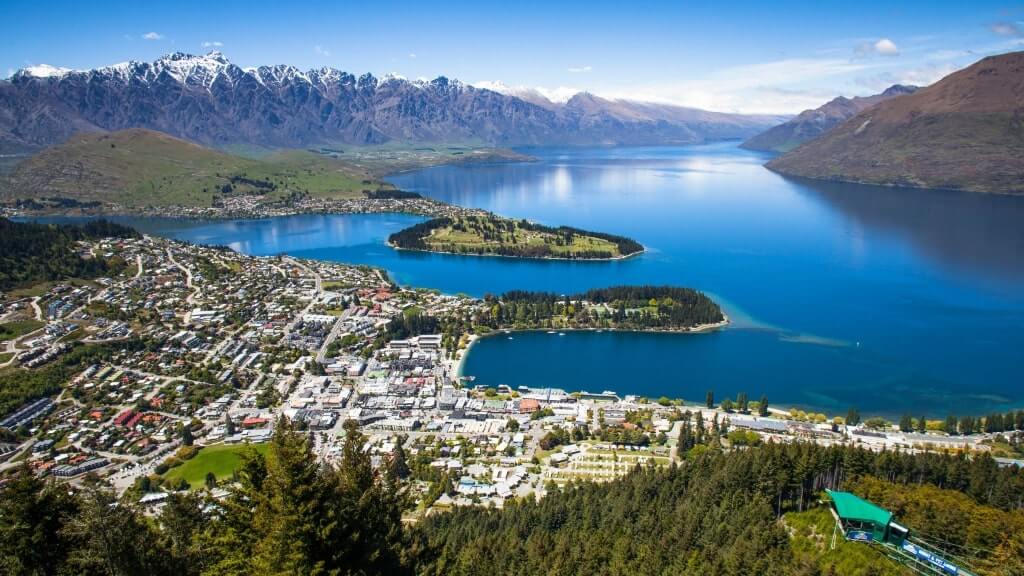 Queenstown, New Zealand, a large lake with mountains surrounding it, a small town