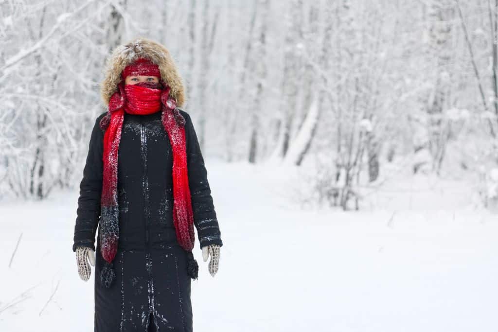 A woman dressed in winter cloths outside in the winter, snow