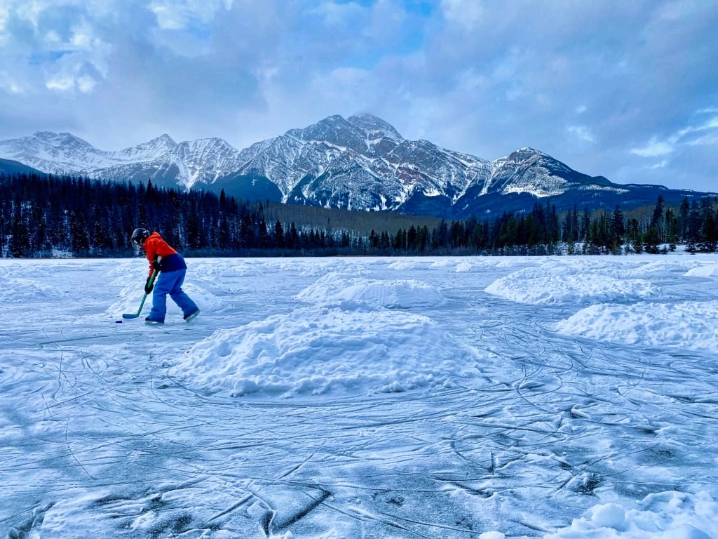 Winter in Jasper, frozen lake, snowy mountain, a kid skating, Places To Visit In Canada In December