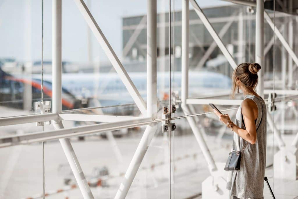 a young woman looking out of a window of an airport, 7 Smart Things To Do Right After Airport Security