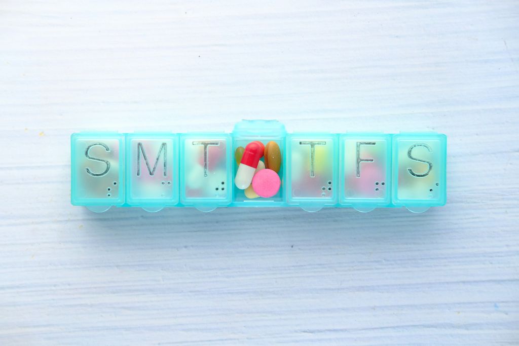 A blue pill organizer, Essential Travel Meds, use a labeled pill organizer or small pouch to keep everything easy to access and neatly stored