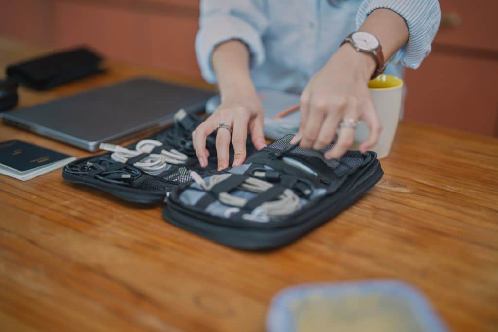 A close up of a woman packing different cables for vacation, what is not a good idea to pack is a ton of gadgets and cables