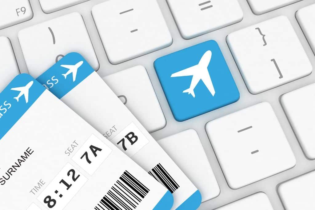 A close up of a white keyboard with the corners of two boarding passes showing at the bottom left
