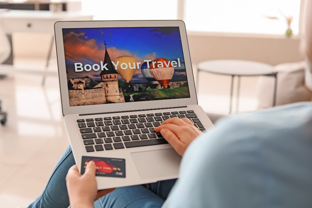 A person having a laptop on their lap and they are looking to book a vacation with their credit card 
