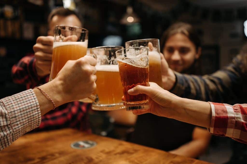 A group of friends cheering with beer glasses, one of the first solo trip safety tips is to not drink too much alcohol