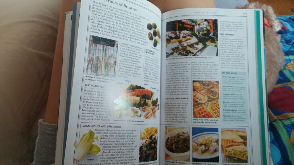A cooking book opened on a page about Brussels foods, one of the souvenir ideas to collect from your travels are cookbooks and recipe cards