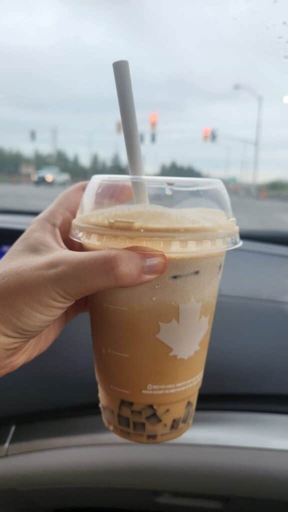 A to go iced coffee plastic cup with a straw in a car, Tim Hortons coffee