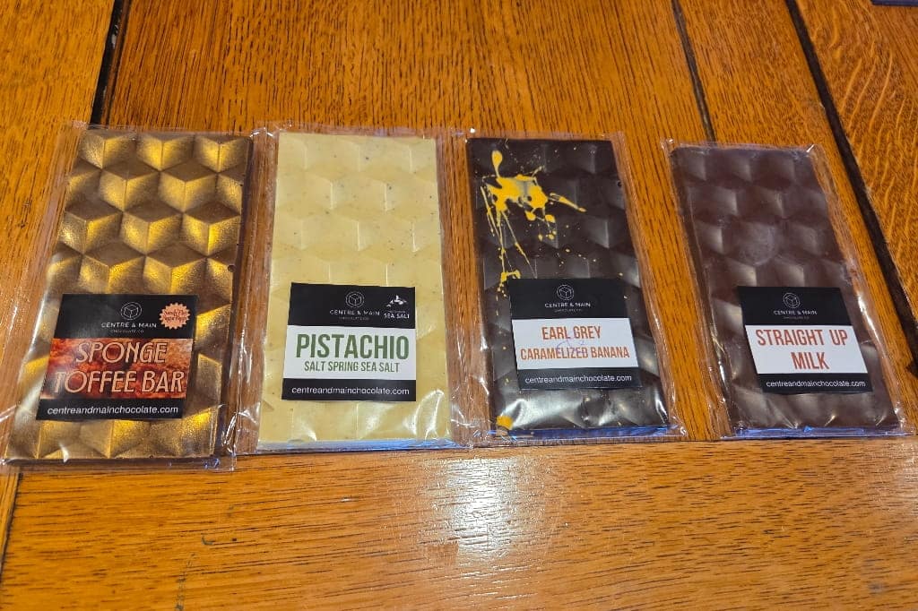 Four different chocolate bars on a wooden table, hand made chocolate